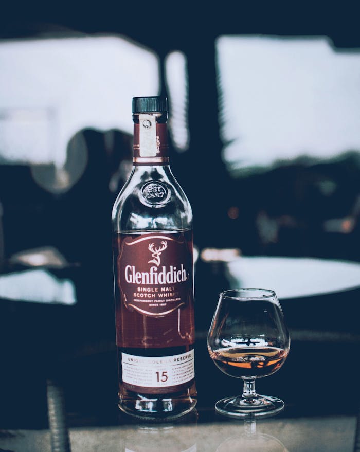 Elegant display of Glenfiddich whisky bottle with a glass indoors.